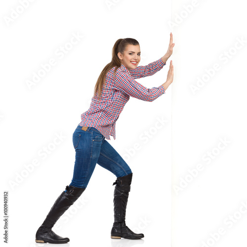 Woman In Lumberjack Shirt Pushing Wall photo