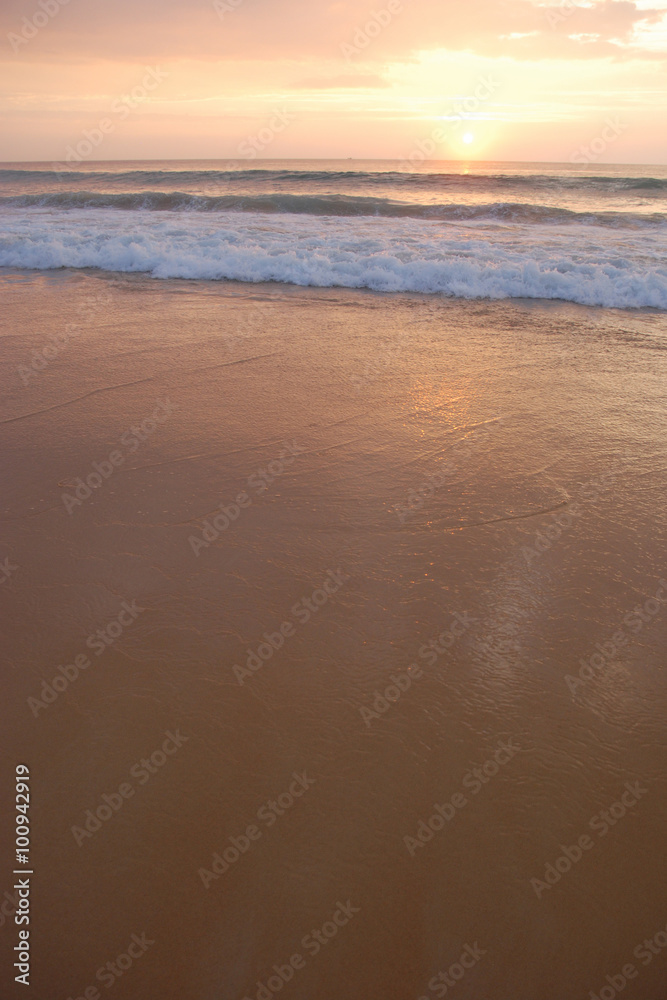 sunset on the smooth sandy beach with white gentle waves, shoot from Phuket island Thailand