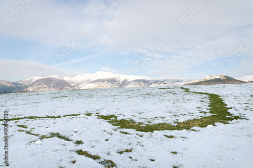 The Lake District, Keswick, England, 01/17/2016, Snowy field with snow covered mountains in the background