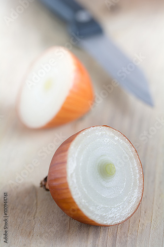 Zwiebeln mit einem Messer liegen auf einem Holzbrett.