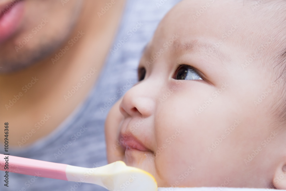 Father feeding baby food to cute newborn baby Father feeding baby food to cute newborn baby