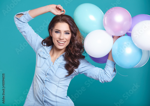 Woman with balloons in studio on a blue background © ZoomTeam