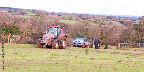 Tableau sur toile Tractor towing a vehicle from a muddy field in the winter