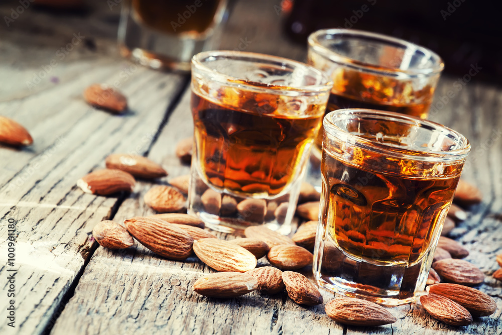 Italian amaretto liqueur with dry almonds on the old wooden back Italian amaretto liqueur with dry almonds on the old wooden back