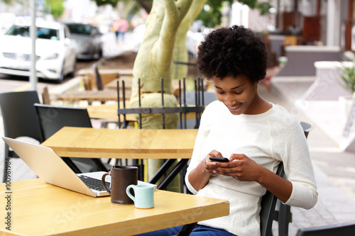 African woman reading text message on mobile phone at a cafe