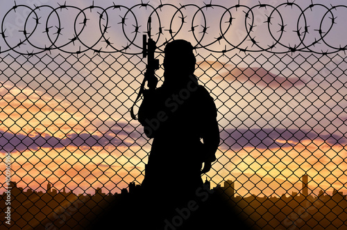 Silhouette of man standing near border fence