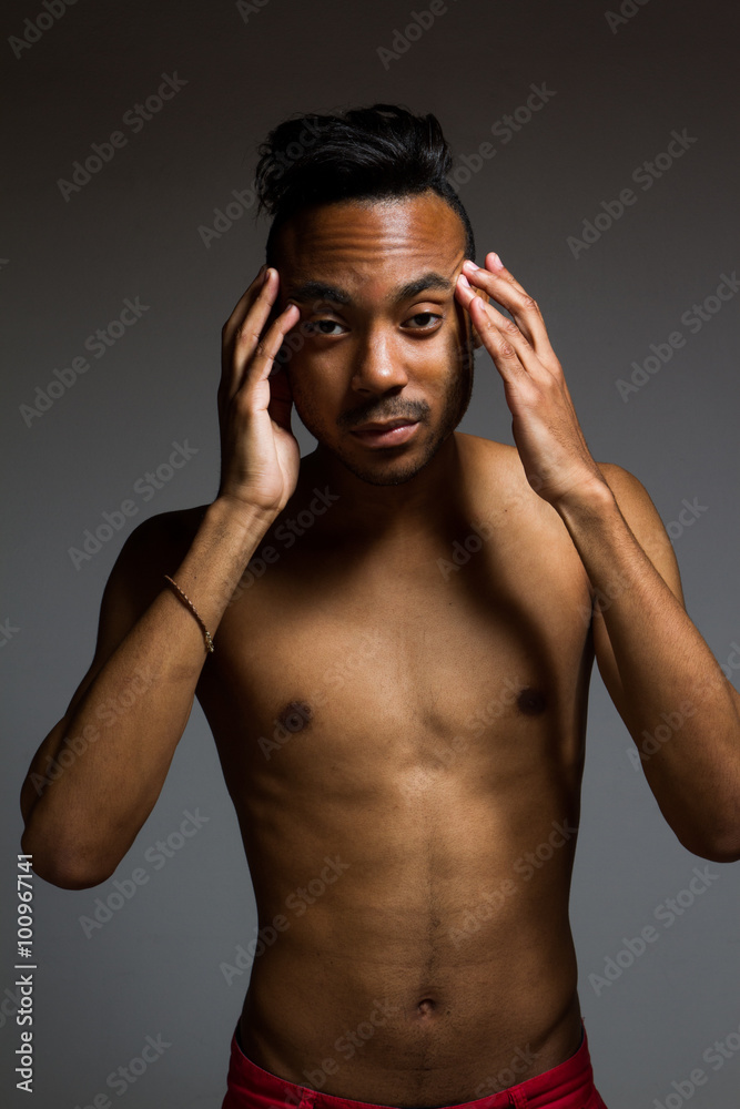 Fototapeta premium Latin man posing indoor over a grey wall.