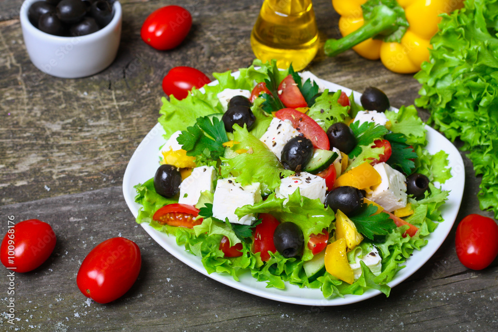 Greek salad with fresh vegetables, feta cheese and black olives on a wooden background Greek salad with fresh vegetables, feta cheese and black olives on a wooden background