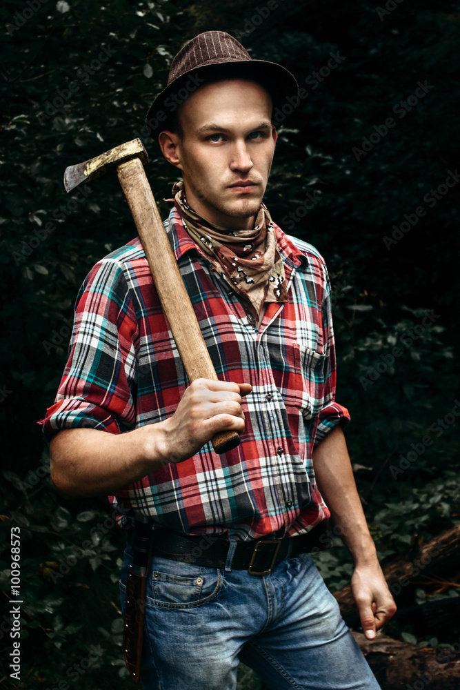 stylish hipster lumberjack with ax in the sunny forest in mounta Stock