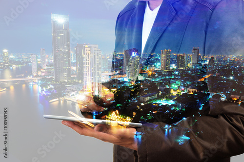 Double exposure of city and businessman using digital tablet Fototapeta