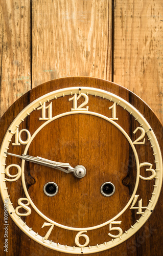 Vintage clock on wooden wall background. Concept of the passage