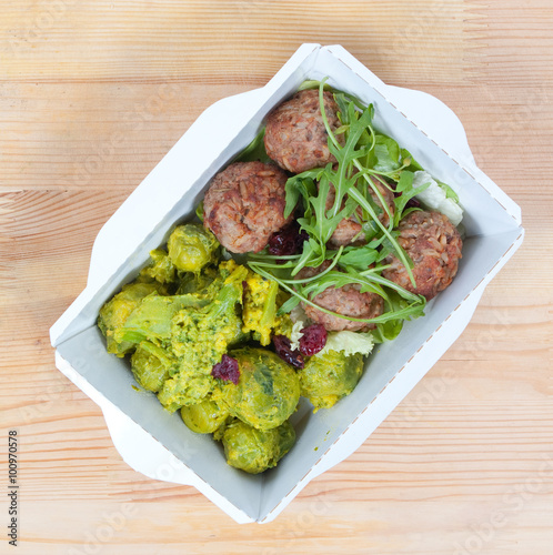 Beef noisettes with garnish and cranberry dauce in a white ecological carton box on a wooden surface photo