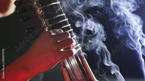 Sitar, a String Traditional Indian Musical Instrument, close-up, blue lens effect. dark background with incense smoke. Evening of ethnic oriental music. Indian Raga