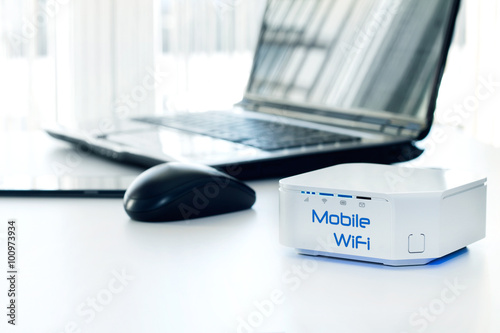 Mobile WiFi router device on the table and notebook on background