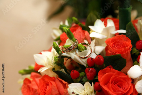 Wedding rings lie on a bouquet of the bride