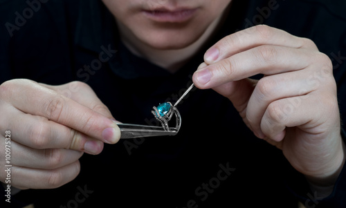 Jeweler holding a ring with a stone. 