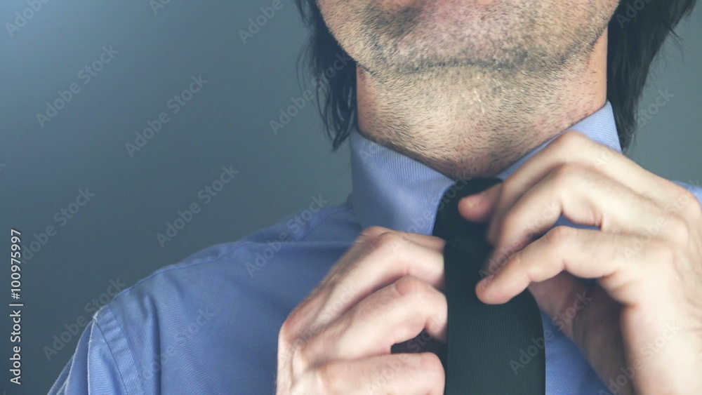 Cool young adult businessman adjusting his necktie in office before important business meeting or interview Cool young adult businessman adjusting his necktie in office before important business meeting or interview