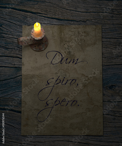 Dum spiro spero latin proverb. While I brethe, I hope. Old paper and candle on rustic wooden table. photo
