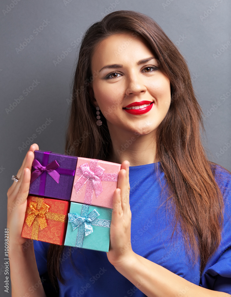 Beautiful girl holding gift boxes on gray background Beautiful girl holding gift boxes on gray background