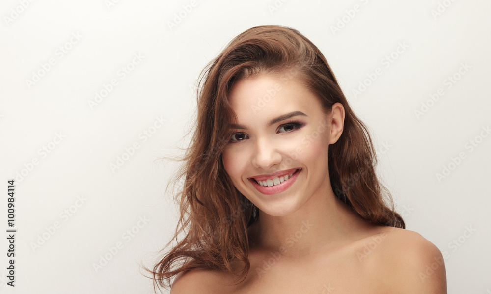 Closeup portrait of young adorable smiling brown-haired woman with bare shoulders