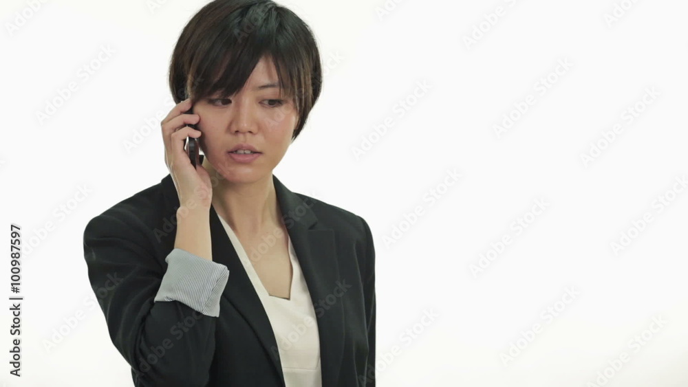 Asian businesswoman talking on phone happily, looks at camera and smiles Asian businesswoman talking on phone happily, looks at camera and smiles