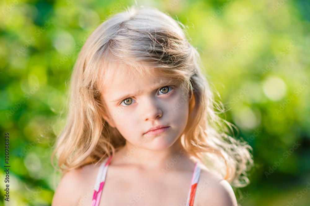 Close-up portrait of thoughtful little girl with long blond hair. Sunny summer day in beautiful park Close-up portrait of thoughtful little girl with long blond hair. Sunny summer day in beautiful park