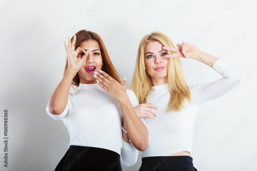 Two women having fun showing sign with hands.