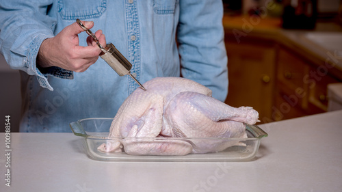 Bilde på lerret Using a stainless injector to prepare a turkey