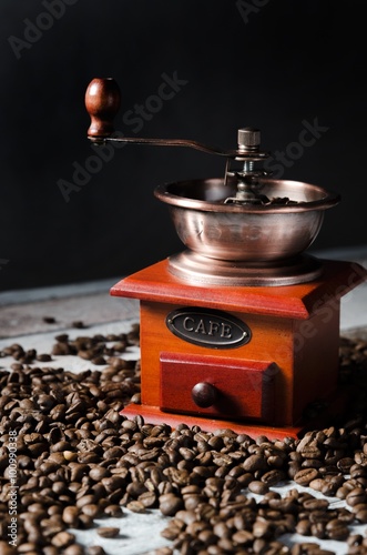 Old retro coffee grinder on wooden background with coffee beans