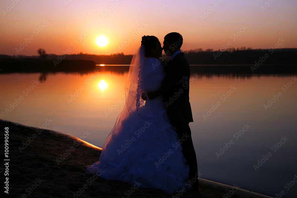the bride and groom look at each other on background of sunset o