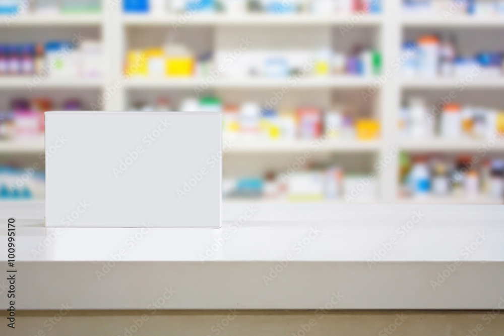 Blank white medicine package on counter with blur shelves of dru Blank white medicine package on counter with blur shelves of dru