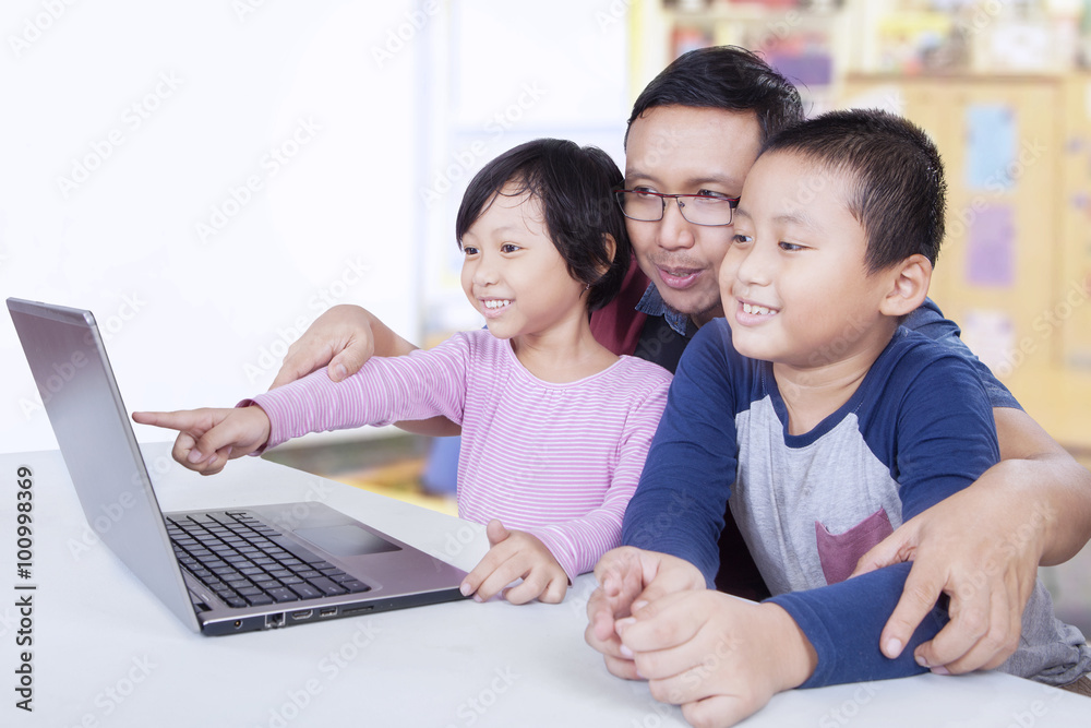 Two children using laptop with teacher in class Two children using laptop with teacher in class