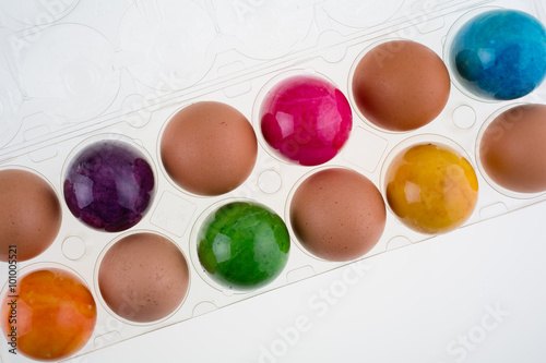 Easter and brown eggs in a clear plastic carton
