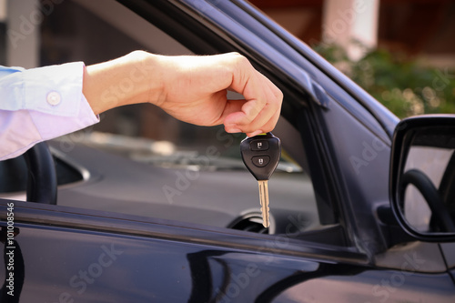 Business man smiling showing key and sit in car
