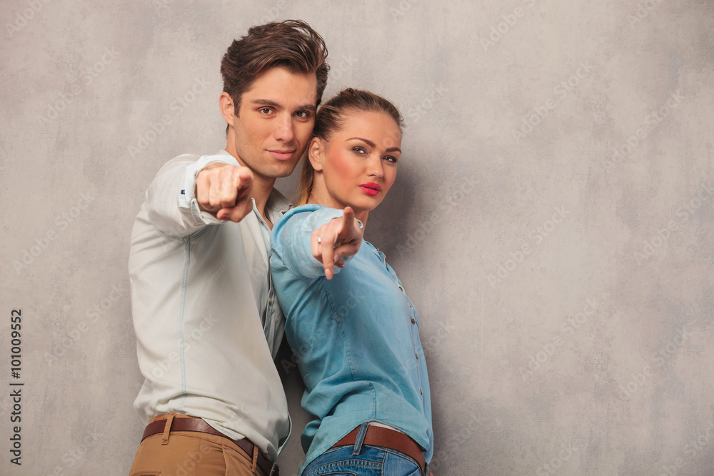 man and woman standing close and pointing fingers in studio