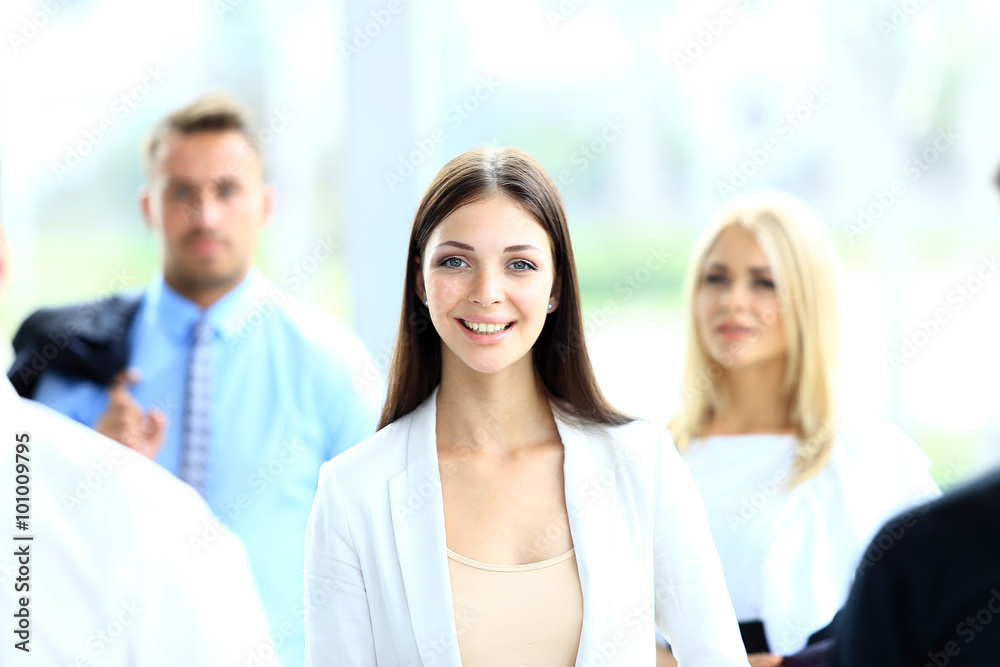 Successful business woman standing with her staff in background at office Successful business woman standing with her staff in background at office
