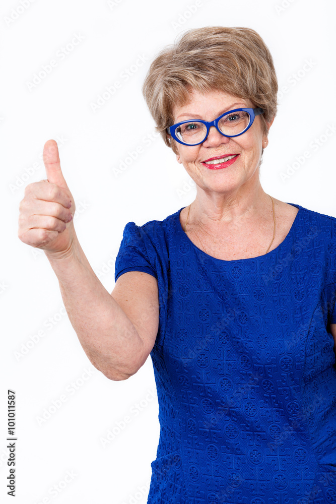 Portrait of toothy smiling elderly woman with thumbs up gesture, looking at camera, white background