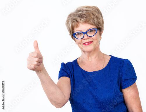 Aged Caucasian woman with thumb up looking at camera with smile  white background