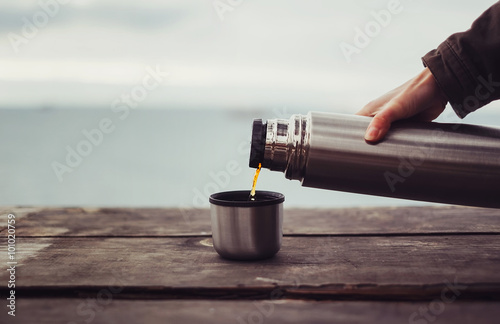Traveler pouring tea from thermos