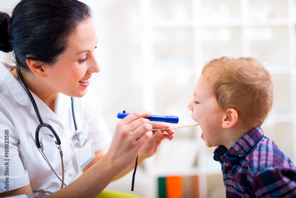 Medical doctor with child in office. Pediatrician examining little boy's throat with tongue depressor Medical doctor with child in office. Pediatrician examining little boy's throat with tongue depressor