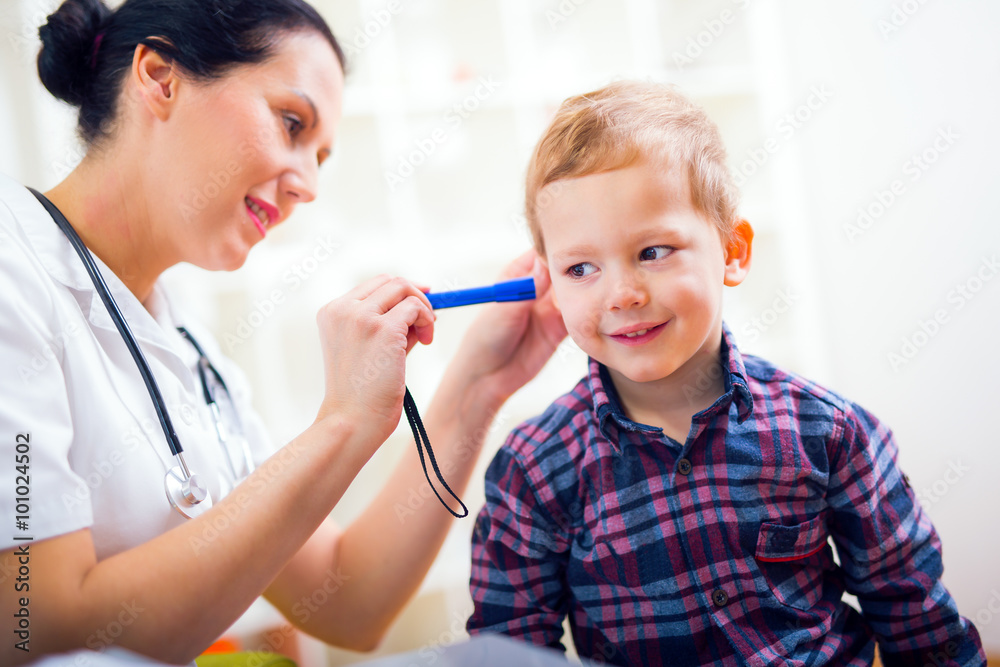 Female doctor examining little child boy. Horizontal view of boy during ear examination Female doctor examining little child boy. Horizontal view of boy during ear examination