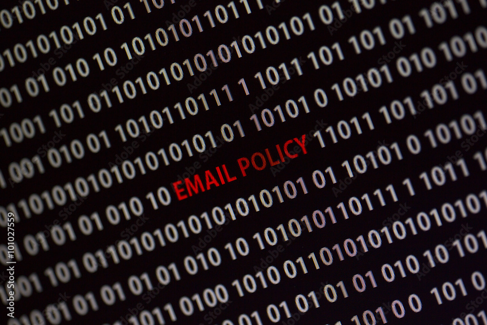'Email policy' text in the middle of the computer screen surrounded by numbers zero and one. Image is taken in a small angle. 'Email policy' text in the middle of the computer screen surrounded by numbers zero and one. Image is taken in a small angle.