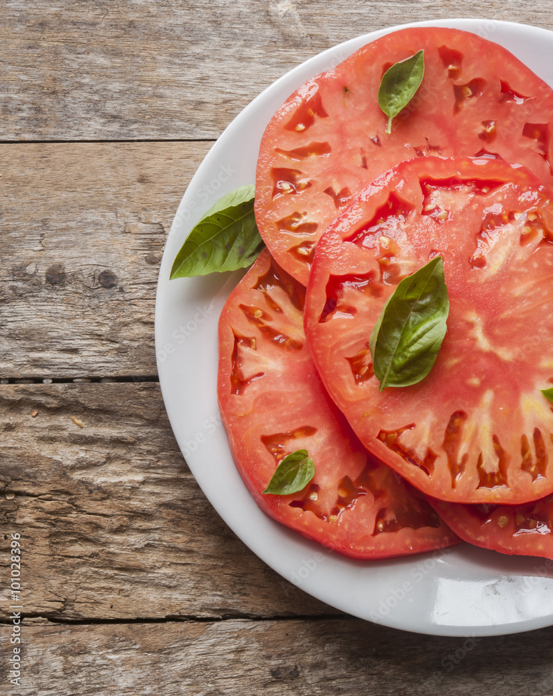 Tomatoes with basil in white plate