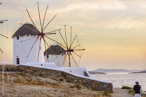  Windmills in Chora,Mykonos,Greece at sunset.Greek whitewashed architecture,a popular landmark,tourist destination on the island of winds,deep blue sky,Aegean sea. Wind mills are now decorative. 