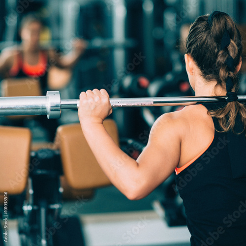Woman exercising in gym with Olmipic barbell