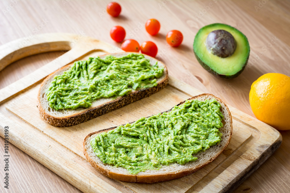 Guacamole and bread. Toast with avocado on wooden cutting board. Warm tone Guacamole and bread. Toast with avocado on wooden cutting board. Warm tone