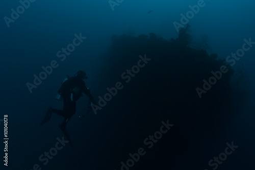 Scuba diver exploring wreck ship in the deep.