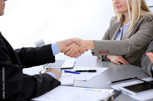 A group of business people at a meeting on the background of office. Business handshake. Focus on a beautiful blonde