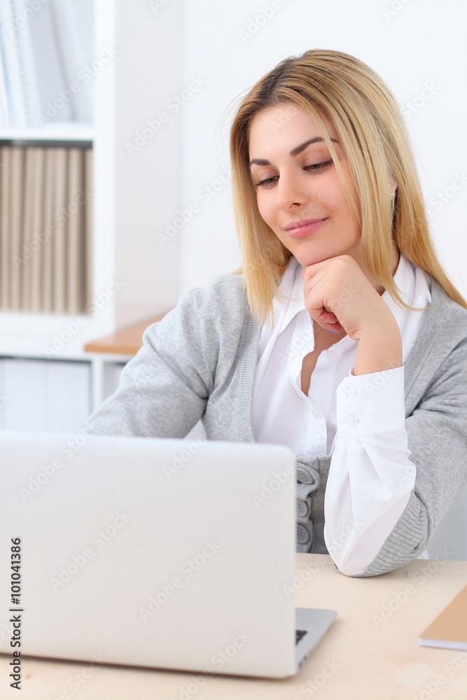 Portrait of young business woman sitting at the desk on office background Portrait of young business woman sitting at the desk on office background