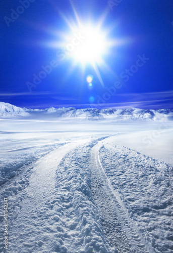 Snow covered road and sun